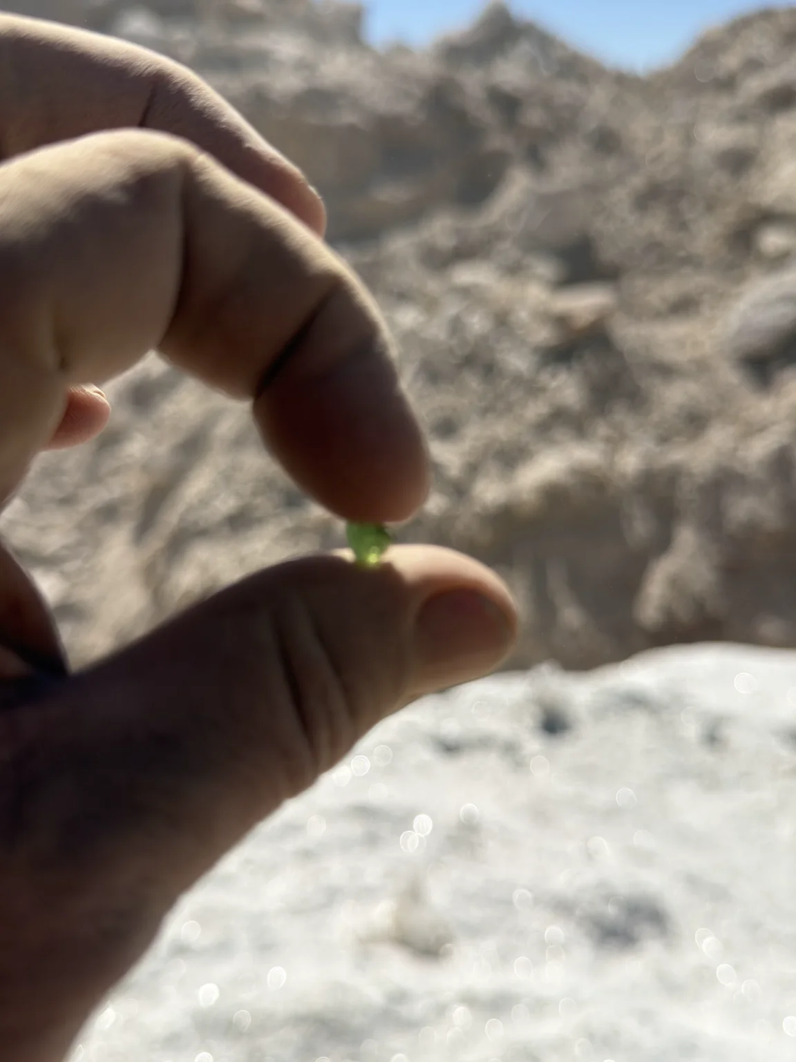 A small green tourmaline fragment held against the mine