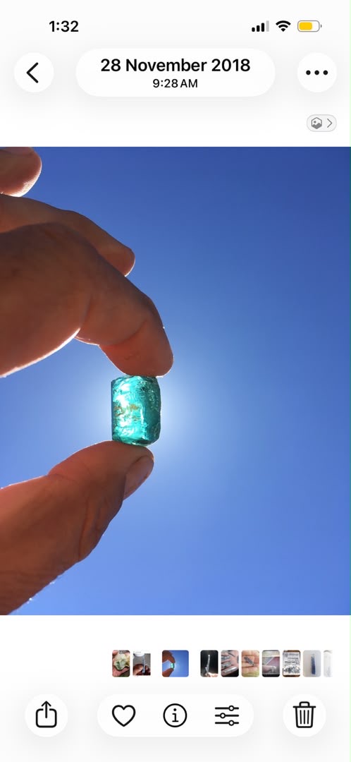 A blue-green tourmaline crystal held up against the Namibian sky